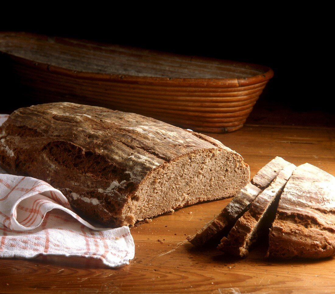 Ein Bauernbrot, angeschnitten, auf Holzuntergrund