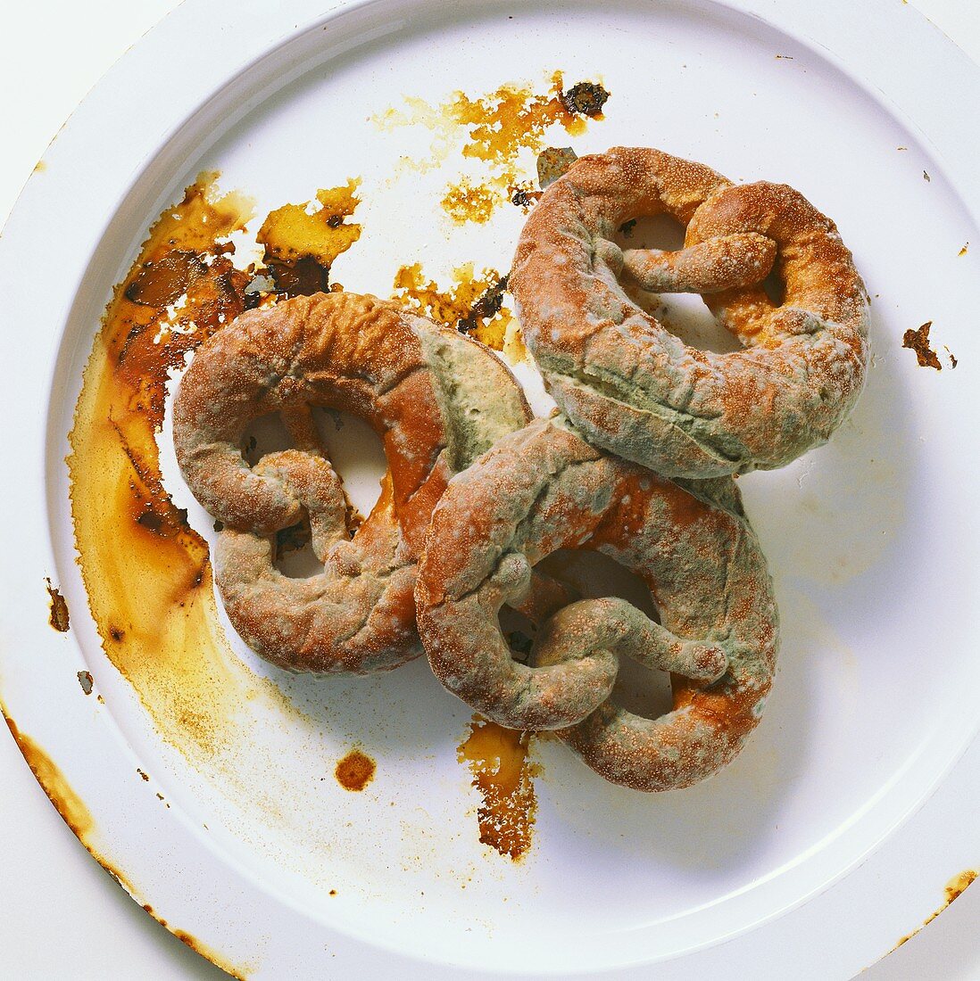 Three mouldy pretzels on a plate