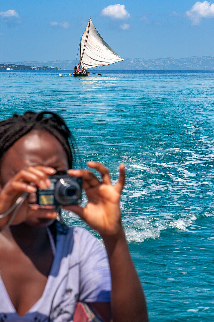 Toutists woman and sailing fishermen boat in Île-à-Vache, Sud Province, Haiti