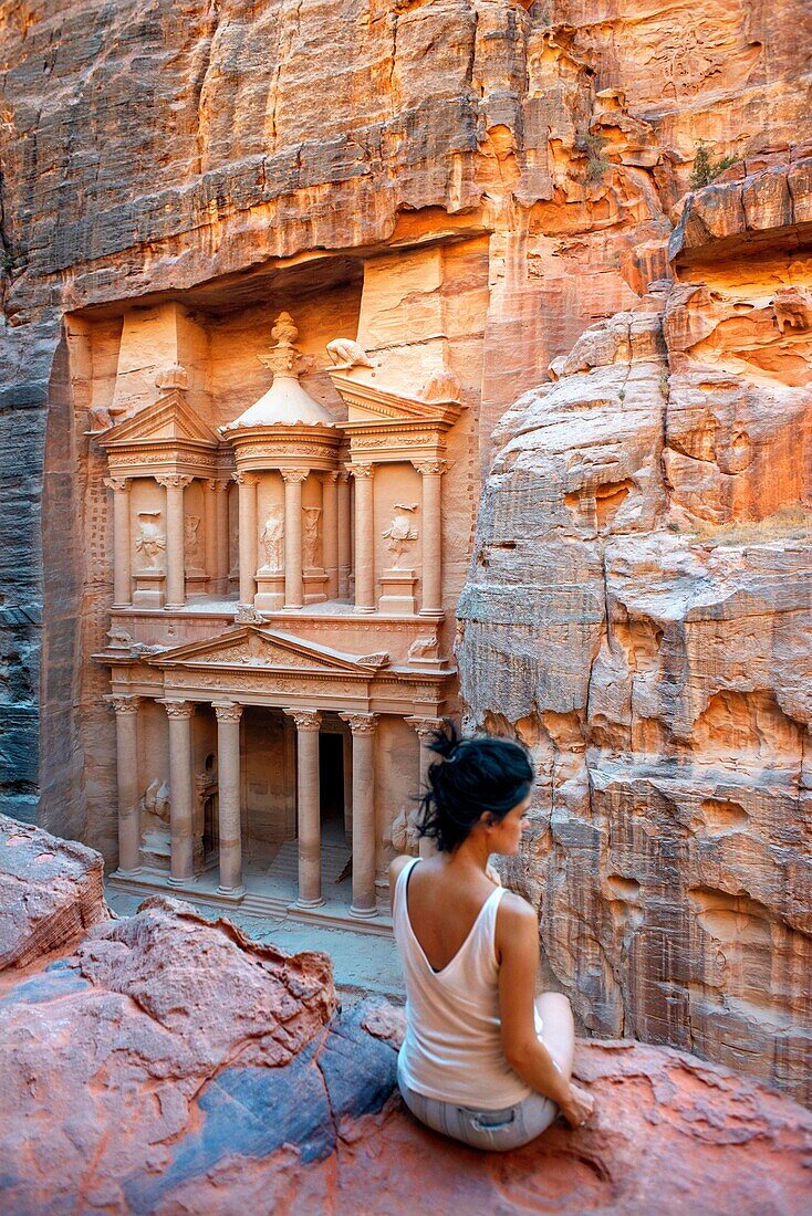 Touristen in der Schatzkammer, El Khazneh, Petra, Jordanien. Petra ist eine historische und archäologische Stadt im südjordanischen Gouvernement Ma'an, die für ihre in Felsen gehauene Architektur und ihr Wasserleitungssystem bekannt ist. Aufgrund der Farbe des Steins, aus dem sie gemeißelt ist, wird Petra auch als Rosenstadt bezeichnet. Sie wurde möglicherweise bereits 312 v. Chr. als Hauptstadt der Nabatäer gegründet und ist ein Symbol für Jordanien sowie die meistbesuchte Touristenattraktion des Landes. Sie liegt am Hang des Jebel al-Madhbah (von einigen als der biblische Berg Hor identifizi