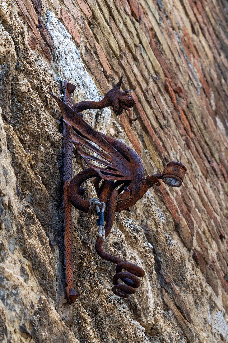 Ein sehr alter Drachenfahnenhalter aus Metall an einem Gebäude in der mittelalterlichen Festungsstadt San Gimignano, Italien