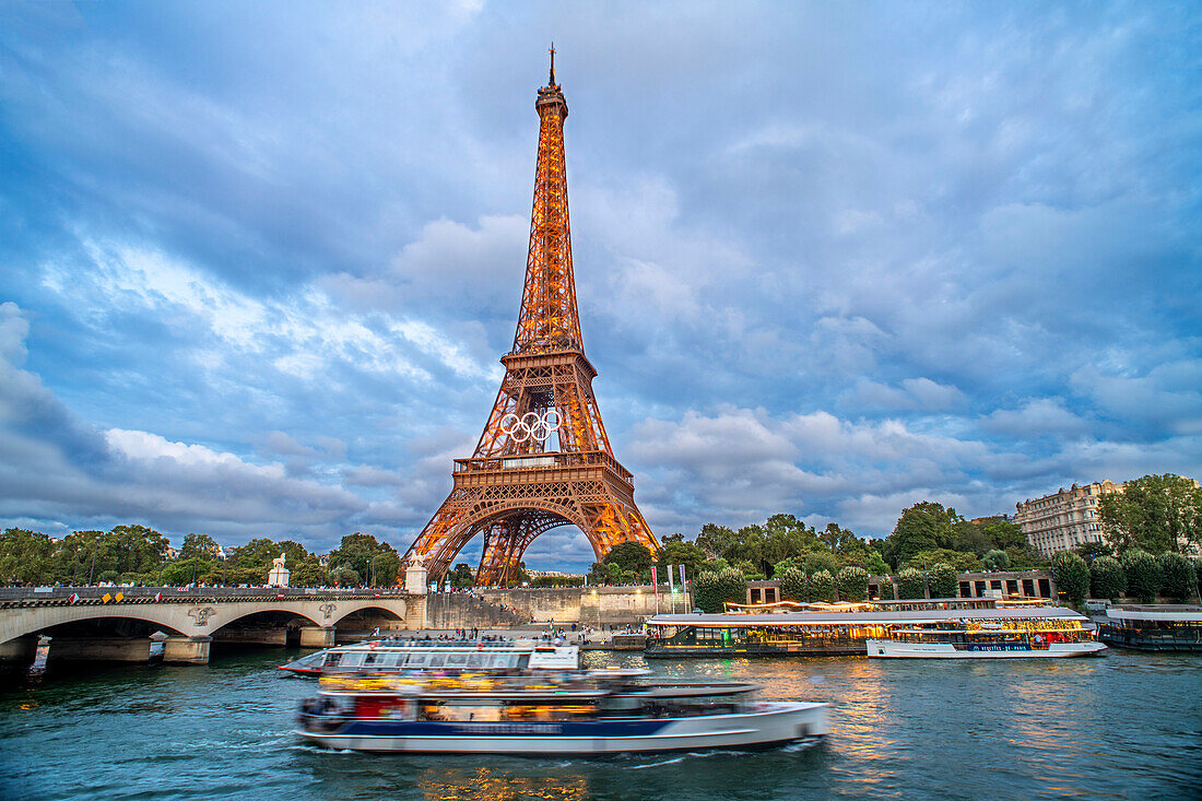 Scenic panorama of Eiffel Tower, Seine River, and pont d'lena in Paris, France; with a cruise passing by ferry