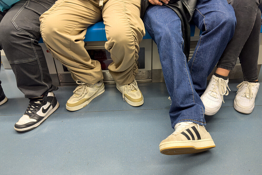 Beine und Füße von jungen Fahrgästen in einem U-Bahn-Zug in Neapel, Italien.