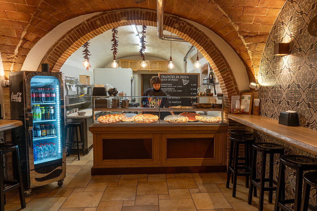 A woman working in a pizzeria on Via San Giovanni in the medieval city of San Gimignano, Italy.