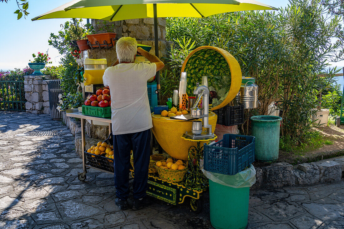 A vendor makes fresh fruit juice drinks at a stand by the Amalfi Coast road in Italy.