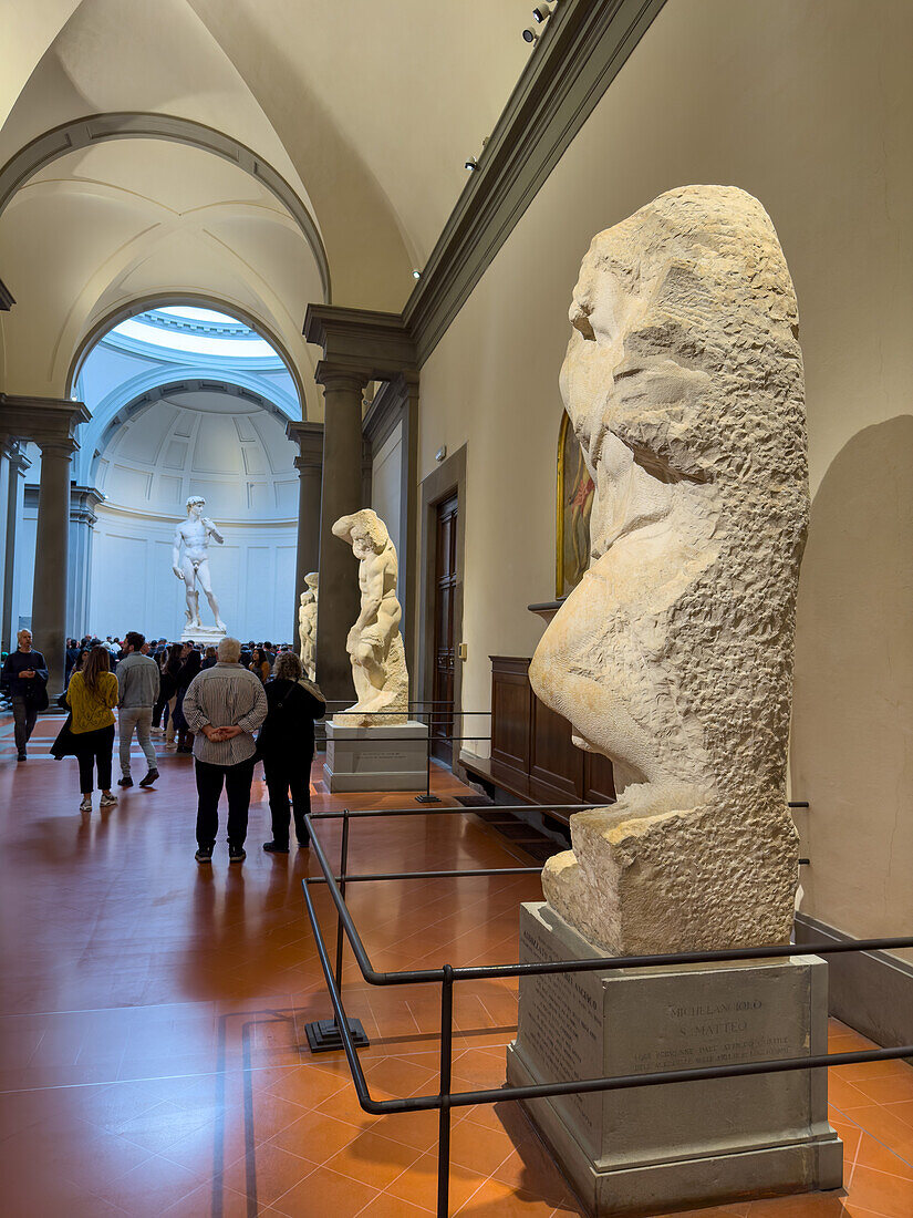 Unfinished works by Michelangelo with David in the background in the Accademia Gallery in Florence, Italy.