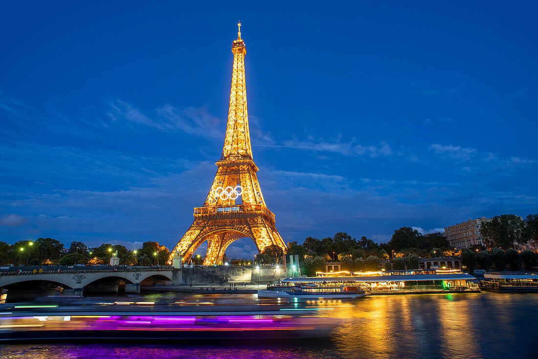 Panorama des Eiffelturms, der Seine und der Pont d'lena in Paris, Frankreich, mit einer vorbeifahrenden Kreuzfahrtfähre.