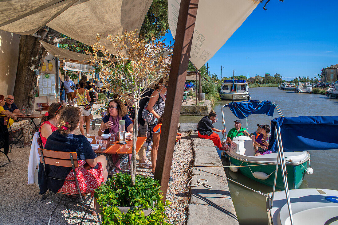 Canal du Midi at bridge and village of Le Somail Aude South of France southern waterway waterways holidaymakers queue for a boat trip on the river, France, Europe