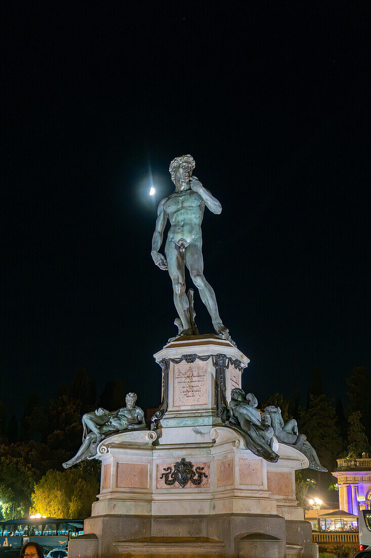 A bronze cast of the David statue with the moon behind on the Piazzale Michelangelo in Florence, Italy.