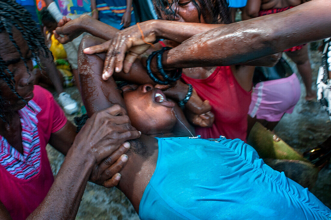 Haiti Voodoo Festival in Saut d'Eau, in Saut d'Eau, Ville Bonheur, Haiti. Tausende von Vodou- und katholischen Anhängern versammelten sich unter dem Wasserfall von Saut d'Eau in Haiti. Die Wallfahrt, die sowohl von Voodou-Anhängern als auch von Katholiken unternommen wird, hat ihren Ursprung in der Sichtung des Bildes der Jungfrau Maria auf einem Palmblatt in der Nähe des Wasserfalls vor einem halben Jahrhundert. Der Katholizismus und die Voodou-Praktiken sind in ihrer haitianischen Form für immer miteinander verwoben. Das Erscheinen eines Regenbogens unter den Wasserfällen soll bedeuten, dass