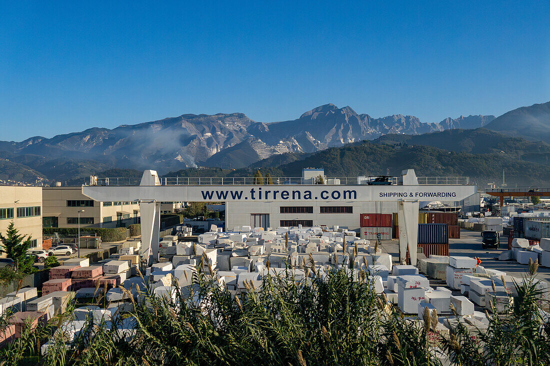 Das Versandlager von Tirrena, einer internationalen Marmorspedition in Carrara, Italien. Im Hintergrund sind die Apuanischen Alpen und die Steinbrüche zu sehen.