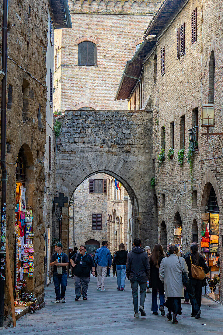 Tourists on Via San Matteo near the 13th Century Chancellery Gate in the medieval city of San Gimignano, Italy.