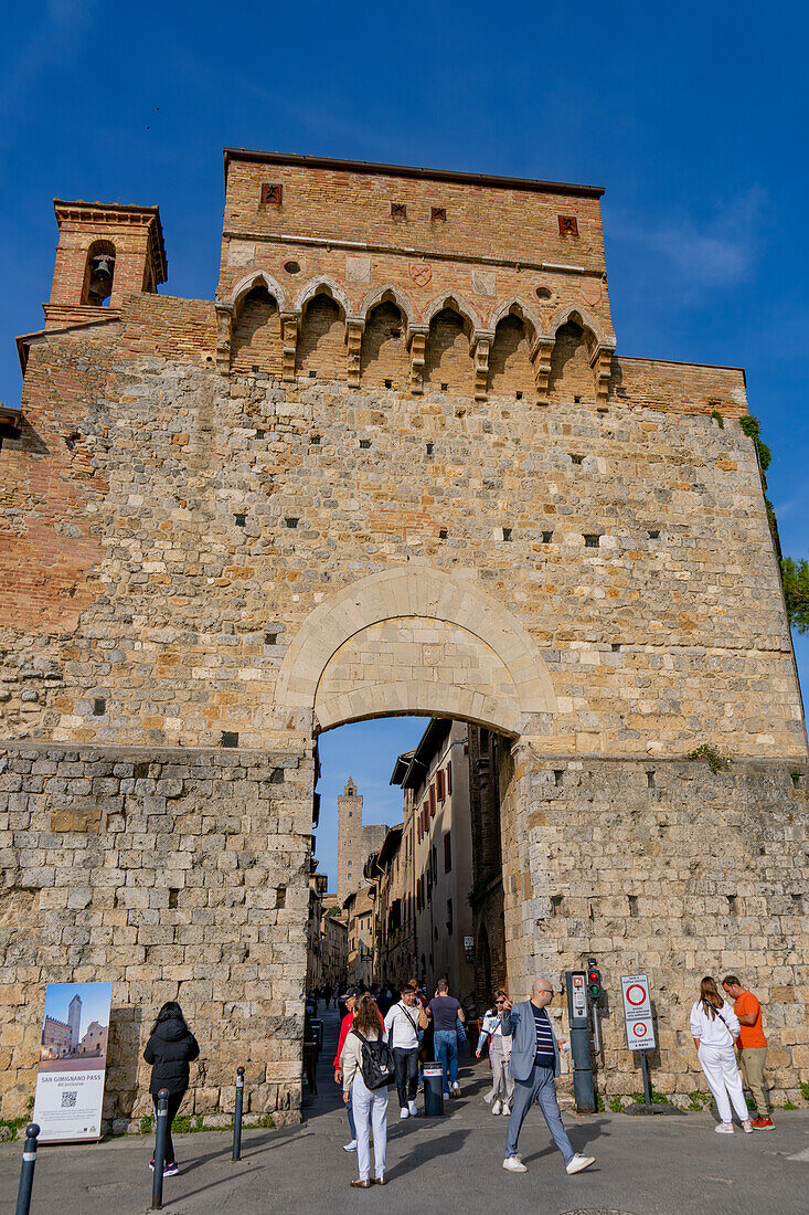 Touristen betreten das Tor Porta San Giovanni in der mittelalterlichen Stadt San Gimignano, Italien.