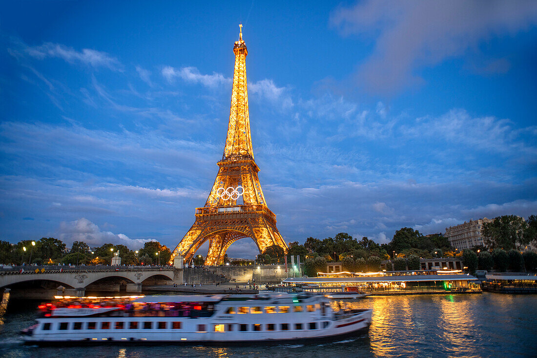 Scenic panorama of Eiffel Tower, Seine River, and pont d'lena in Paris, France; with a cruise passing by ferry