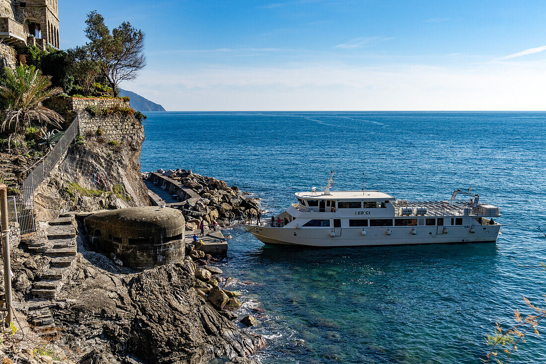 A passenger ferry boat docks at Monterosso al Mare, Cinque Terre, Italy. At left is a World War II pillbox.