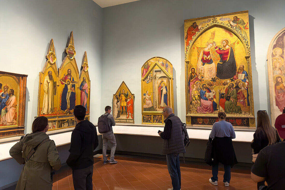 Besucher betrachten Renaissance-Gemälde in einer Ausstellungshalle in der Accademia-Galerie in Florenz, Italien. Diese Gemälde befinden sich im Saal Giovanni da Milano und Orcagna des Museums.