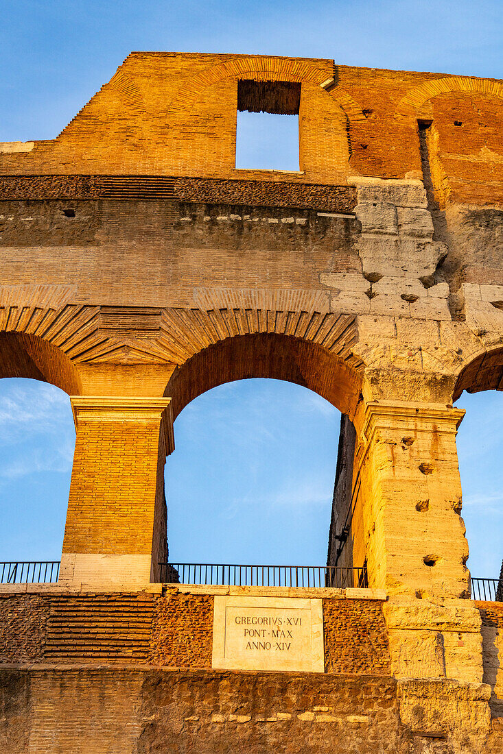 The ancient Roman Colosseum or Flavian Amphitheater with golden sunset light in Rome, Italy.