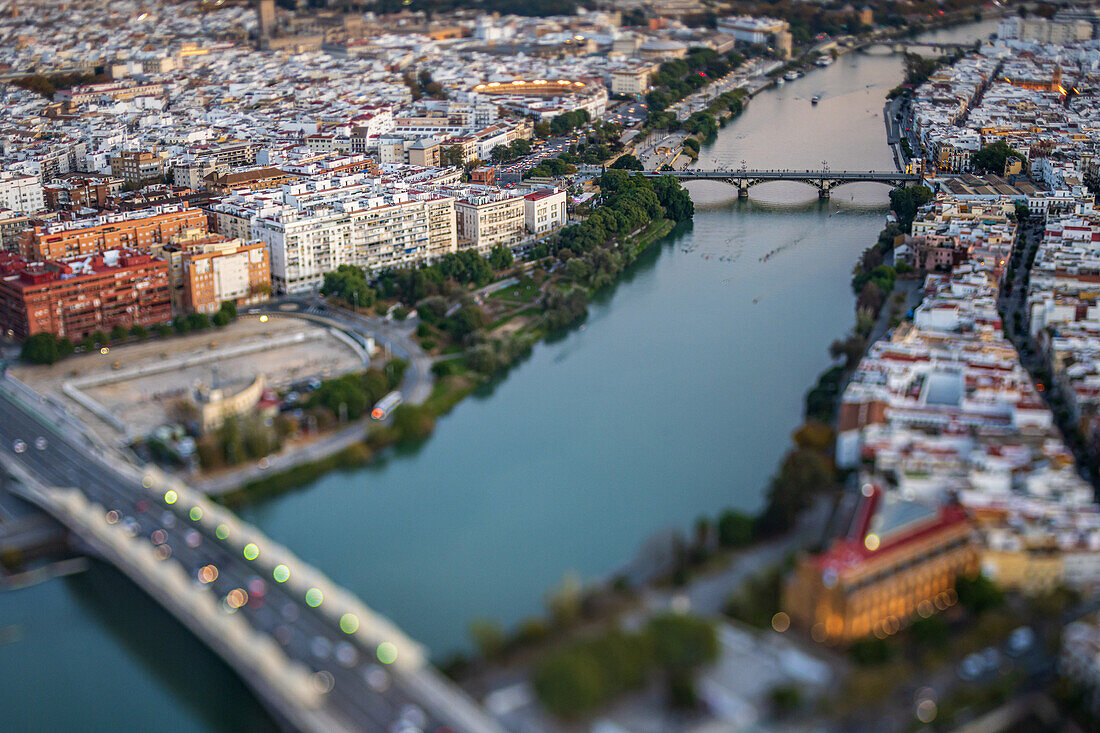 Der Sonnenuntergang wirft ein warmes Licht über den Rio Guadalquivir und die Triana-Brücke in Sevilla und zeigt die pulsierende Architektur und das Leben der Stadt.