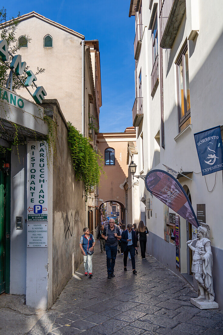 Touristen spazieren auf der schmalen Via Antonino Sersale im historischen Zentrum von Sorrento, Italien.