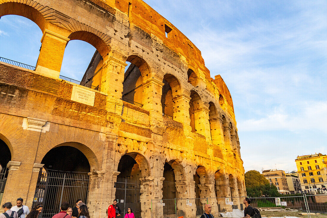 The ancient Roman Colosseum or Flavian Amphitheater with golden sunset light in Rome, Italy.