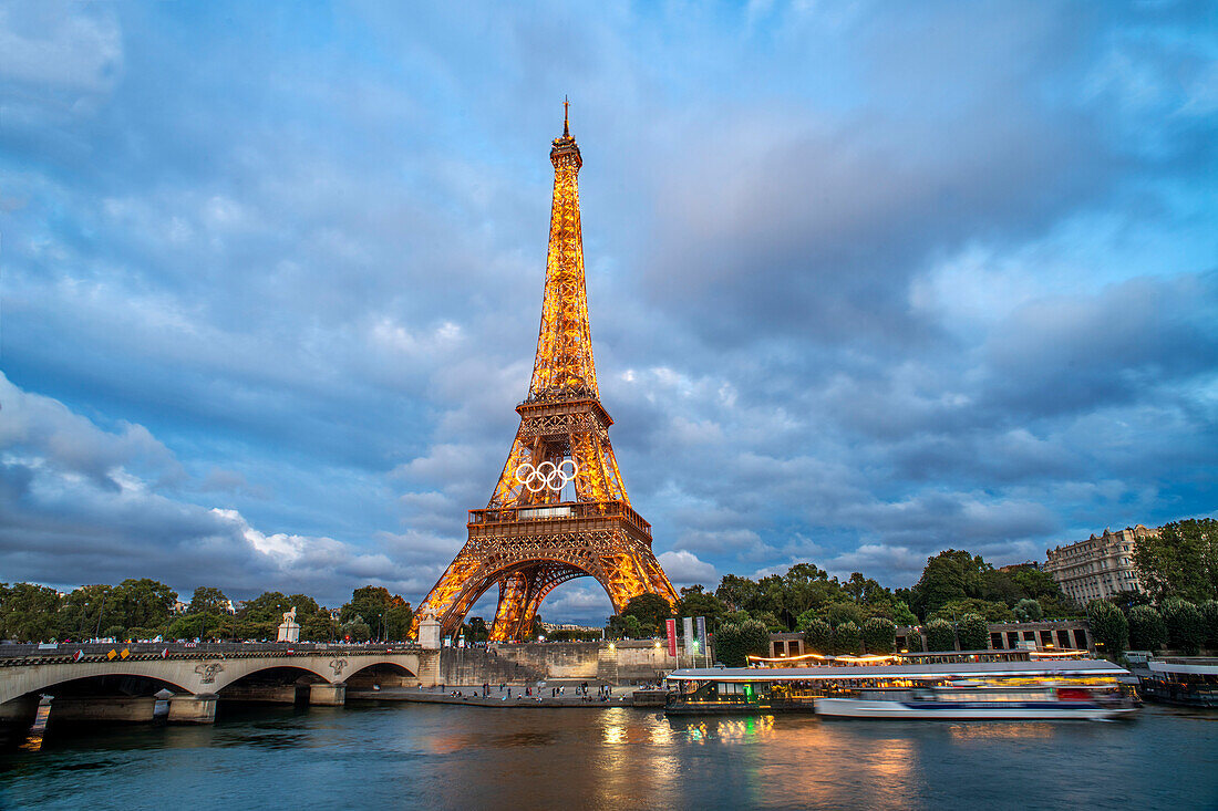 Panorama des Eiffelturms, der Seine und der Pont d'lena in Paris, Frankreich, mit einer vorbeifahrenden Kreuzfahrtfähre.