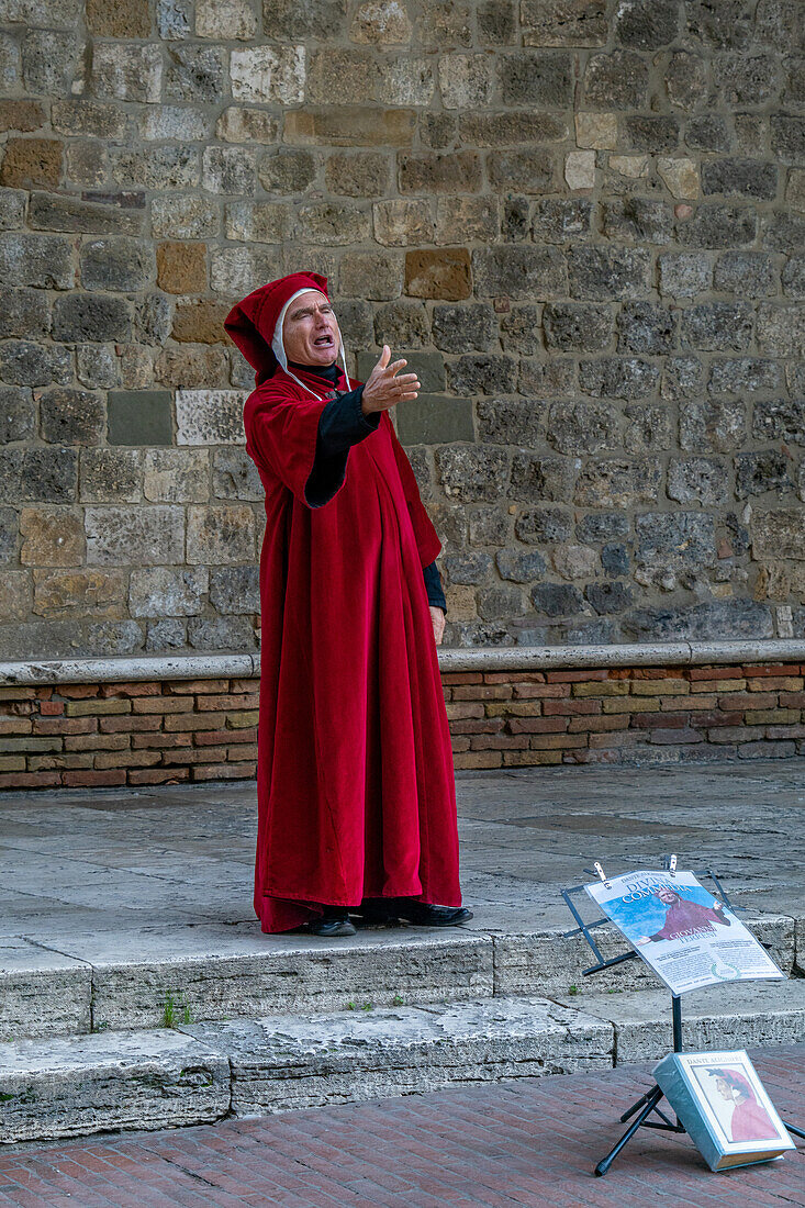 An actor in costume imitates Dante on the street in the medieval walled town of San Gimignano, Italy.