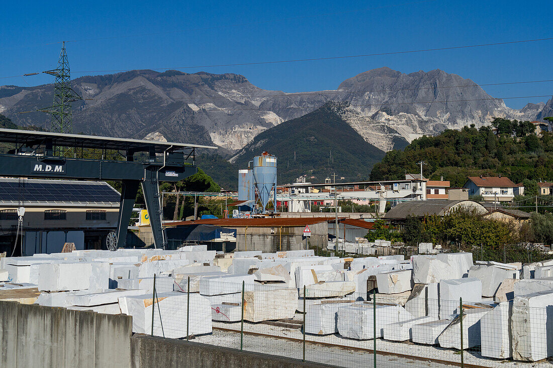 Storage yard and gantry crane of a marble supplier in Carrara, Italy with the quarries in the Apuan Alps behind.