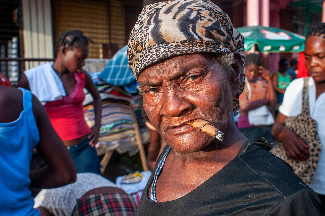 Woman smoking in a local market and houses in the historic colonial old town, Jacmel city center, Haiti, West Indies, Caribbean, Central America