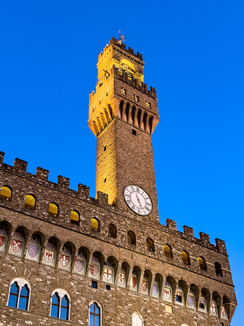 Der Arnolfo-Turm und der Palazzo Vecchio werden in der Dämmerung in Florenz, Italien, beleuchtet.