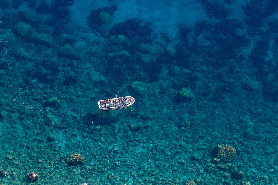 Ein Ausflugsboot mit Passagieren im kristallklaren Wasser des Tyrrhenischen Meeres bei der Insel Capri, Italien.