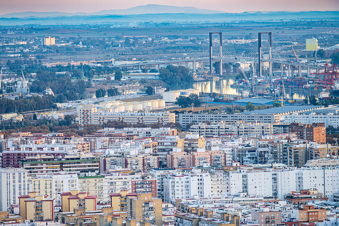 Stadtlandschaft mit Los Remedios in Sevilla mit der Centenario-Brücke und dem Hafen im Hintergrund bei Sonnenuntergang.