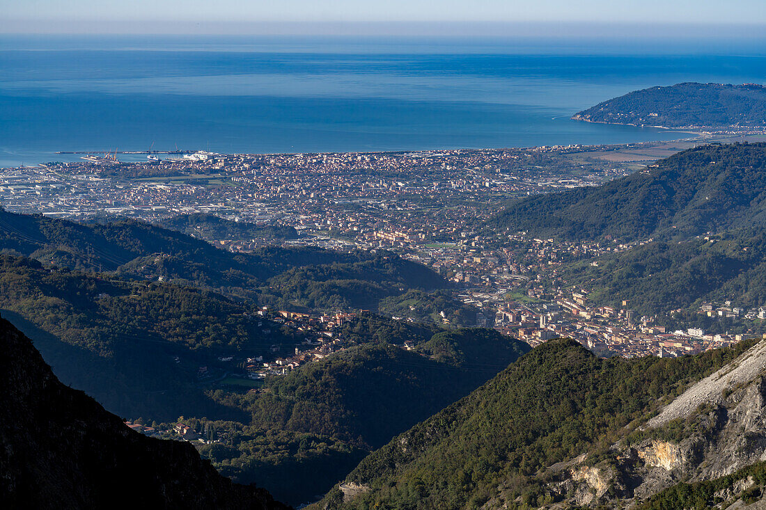 Ein Blick über Carrara und seinen Hafen, die Marina di Carrara, und das Ligurische Meer von den Apuanischen Alpen in Italien.