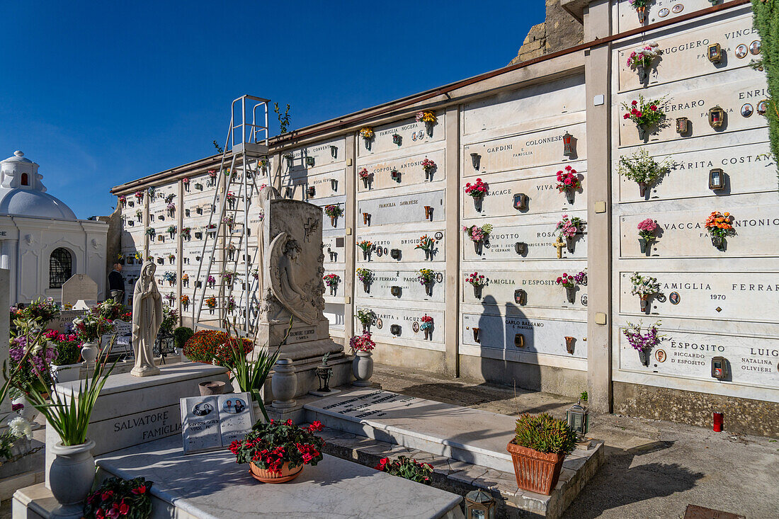 Blumen schmücken die Mausoleumsnischen auf einem Friedhof in Anacapri auf der Insel Capri, Italien.