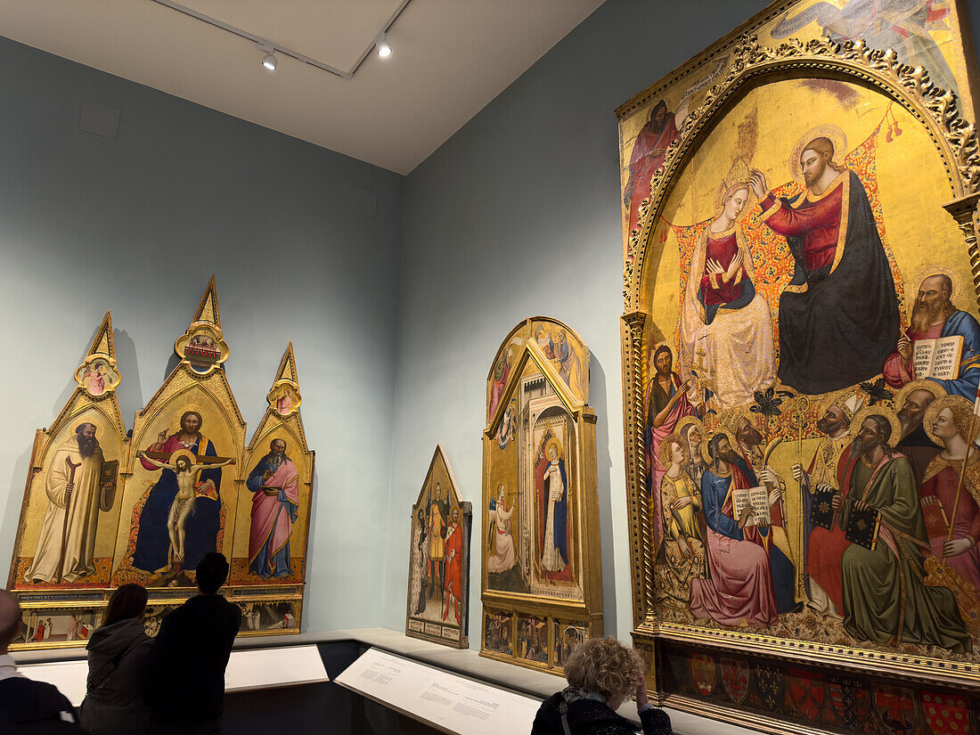 Besucher betrachten Renaissance-Gemälde in einer Ausstellungshalle in der Accademia-Galerie in Florenz, Italien. Diese Gemälde befinden sich im Saal Giovanni da Milano und Orcagna des Museums.