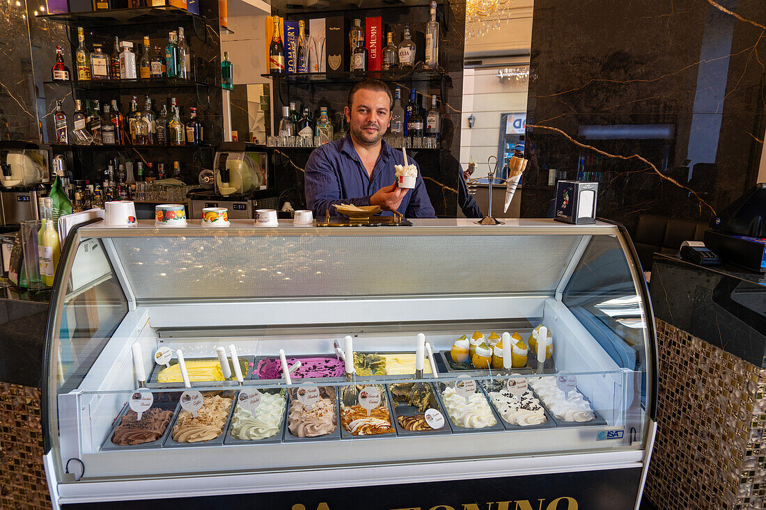 A vendor in a gelateria with a cup of gelato in Sorrento, Italy.