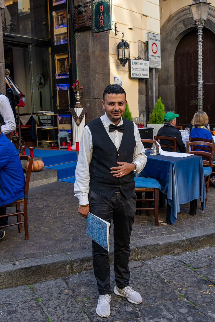 Ein Kellner posiert für ein Foto vor einem Restaurant in Sorrento, Italien.