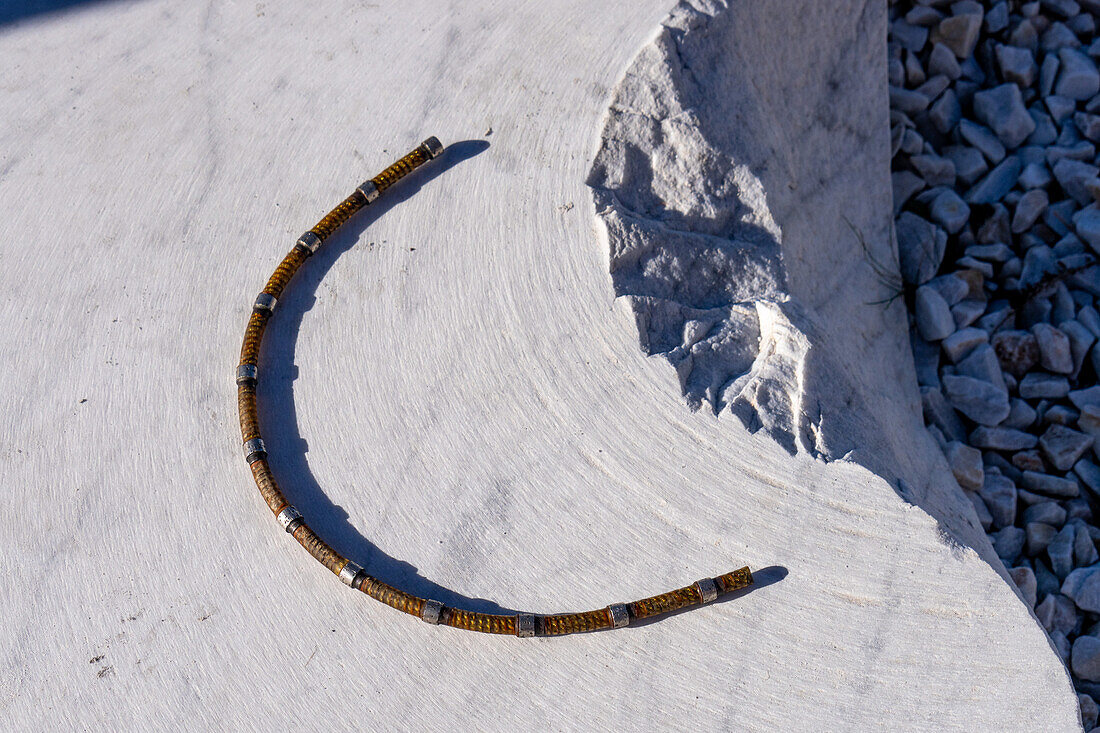 A segment of the diamond-coated wire used to cut blocks of marble from the quarry in Carrara, Italy. Note the curved cutting marks in the marble surface.