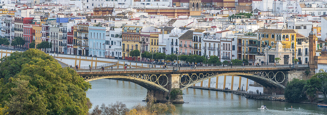 Historic Triana Bridge and colorful Calle Betis by the Guadalquivir River in Seville.