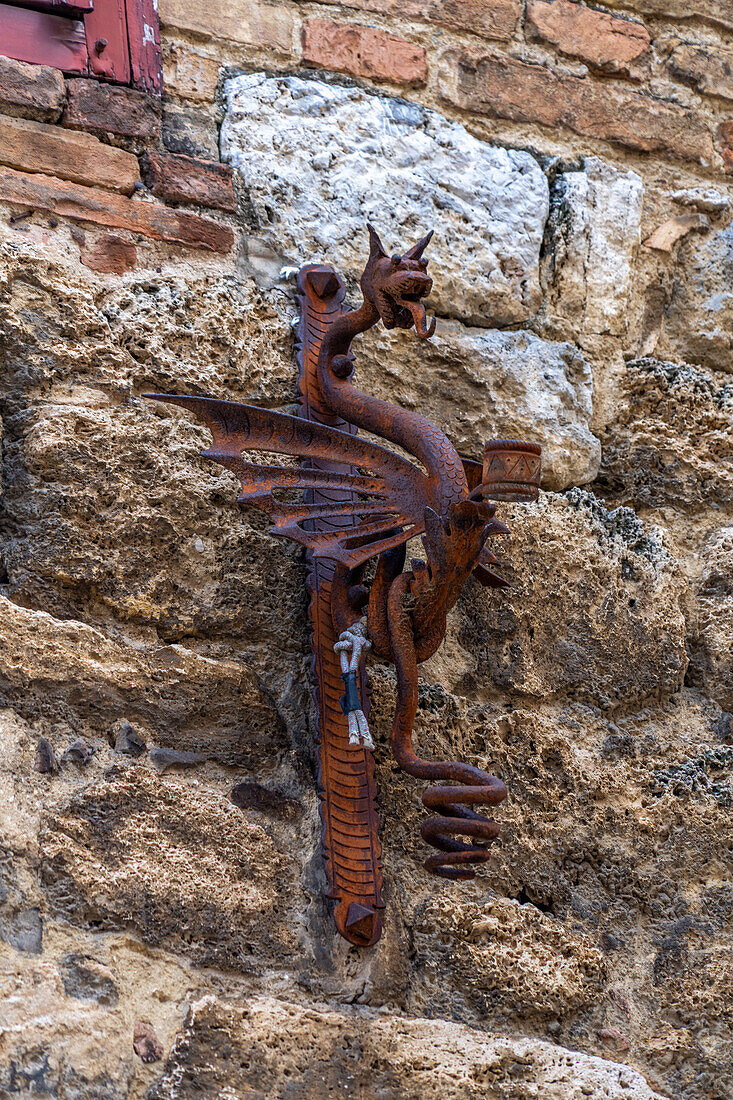 A very old metal dragon flag holder on a building in the medieval walled town of San Gimignano, Italy.