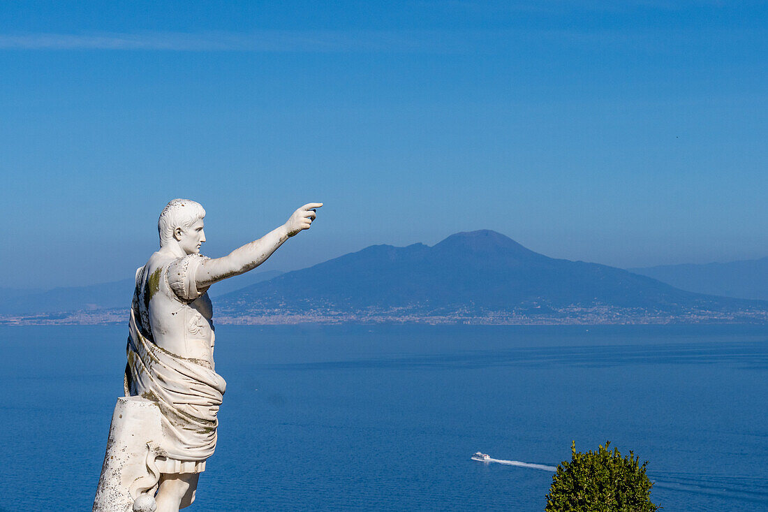 A statue of Augustus Caesar on a cliff-top patio at the Hotel Augustus Caesar in Anacapri, Capri, Italy. Mount Vesuvius is visible across the Bay of Naples.