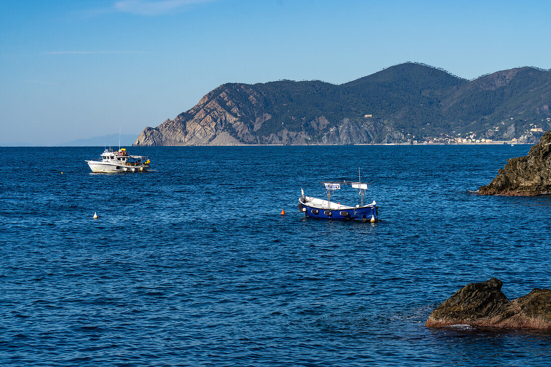 Fishing boats off the rugged coast of the Cinque Terre town of Manarola, Italy. In the distance is the town of Monterosso al Mare.