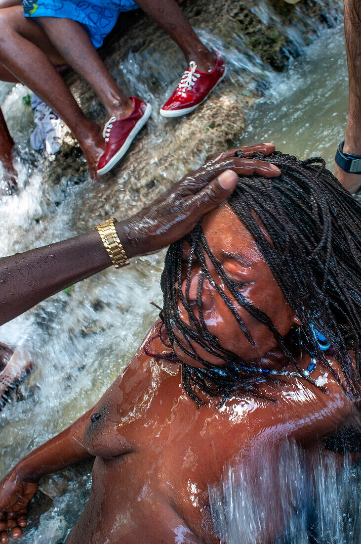 Haiti Voodoo Festival in Saut d'Eau, in Saut d'Eau, Ville Bonheur, Haiti. Tausende von Vodou- und katholischen Anhängern versammelten sich unter dem Wasserfall von Saut d'Eau in Haiti. Die Wallfahrt, die sowohl von Voodou-Anhängern als auch von Katholiken unternommen wird, hat ihren Ursprung in der Sichtung des Bildes der Jungfrau Maria auf einem Palmblatt in der Nähe des Wasserfalls vor einem halben Jahrhundert. Der Katholizismus und die Voodou-Praktiken sind in ihrer haitianischen Form für immer miteinander verwoben. Das Erscheinen eines Regenbogens unter den Wasserfällen soll bedeuten, dass