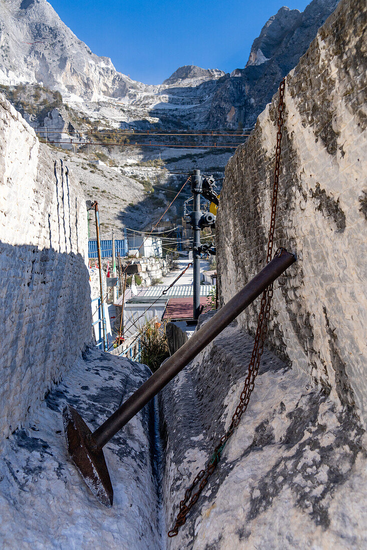 Nachbildung eines römischen Zweizackenhammers zum Spalten von Marmorblöcken. Steinbruchmuseum Fantiscritti, Carrara, Italien. Auf dem Berggipfel dahinter ist ein Steinbruch zu sehen.