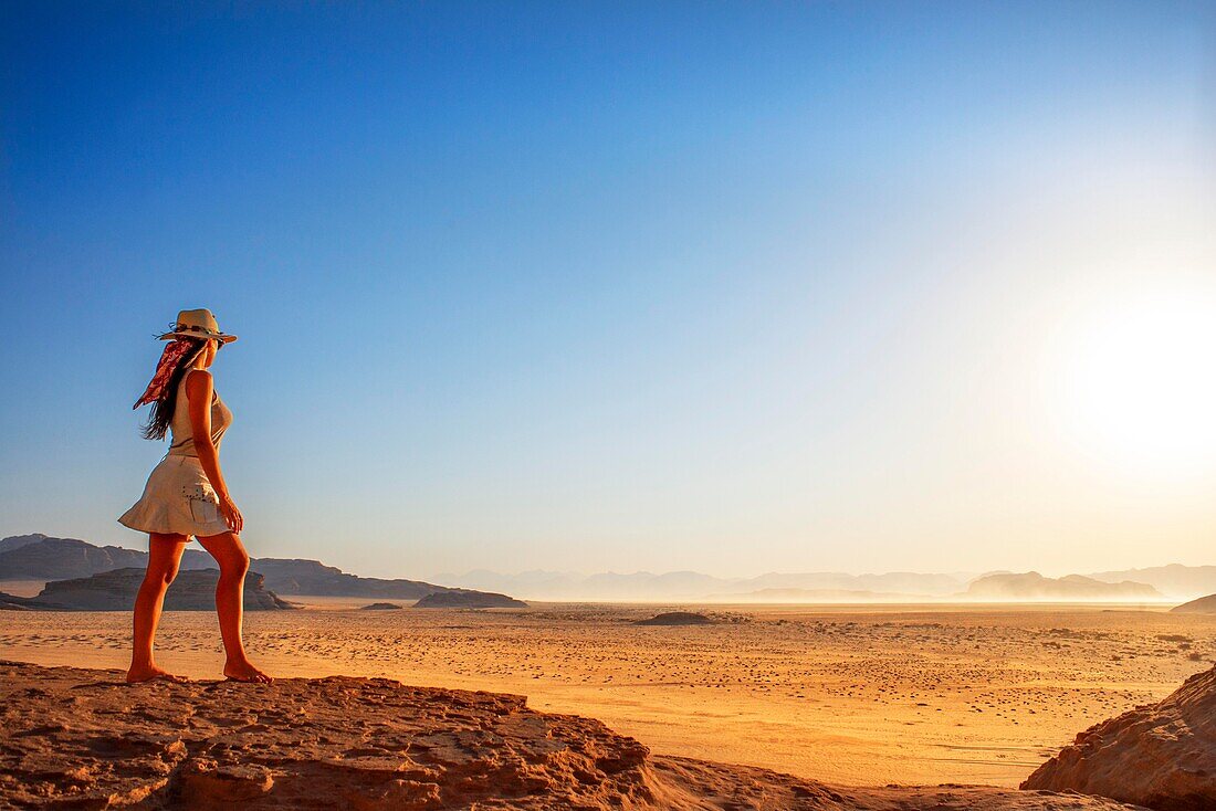 Touristin blickt bei Sonnenuntergang über den roten Sand der Wüste von Wadi Rum, Jordanien