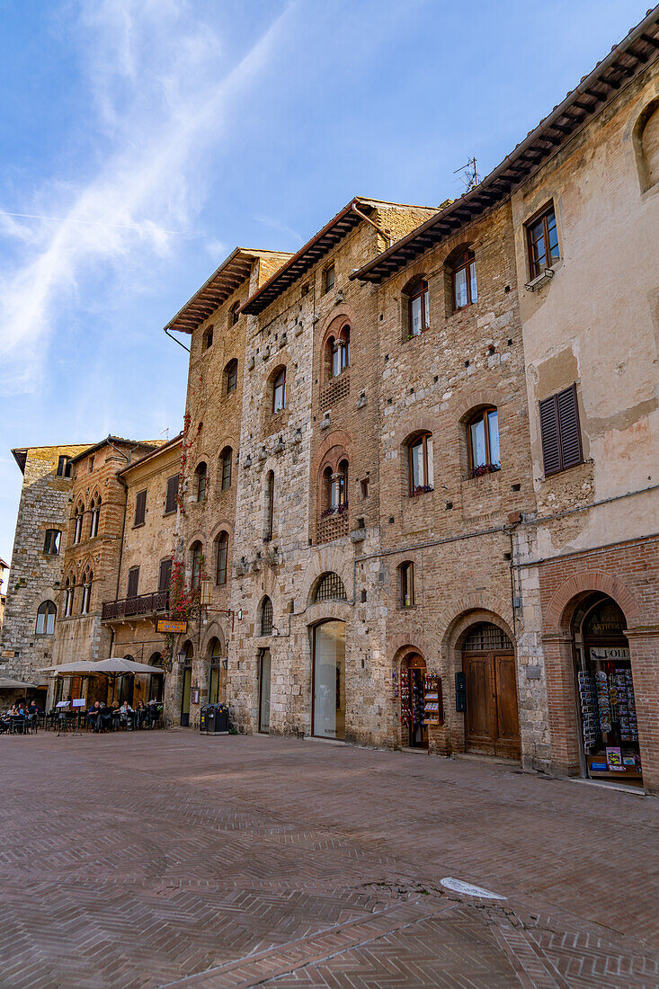 Mittelalterliche Gebäude rund um die Piazza della Cisterna in der ummauerten Stadt San Gimignano, Italien.