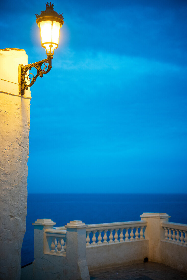 Vintage street lamp shining against a serene coastal view in iconic Nerja, Spain