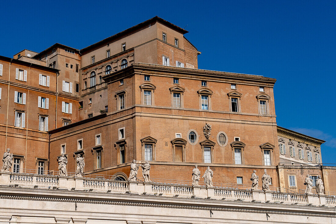 Statues on the portico around Saint Peter's Square in Vatican City in Rome, Italy with the Apostolic Palace behind.