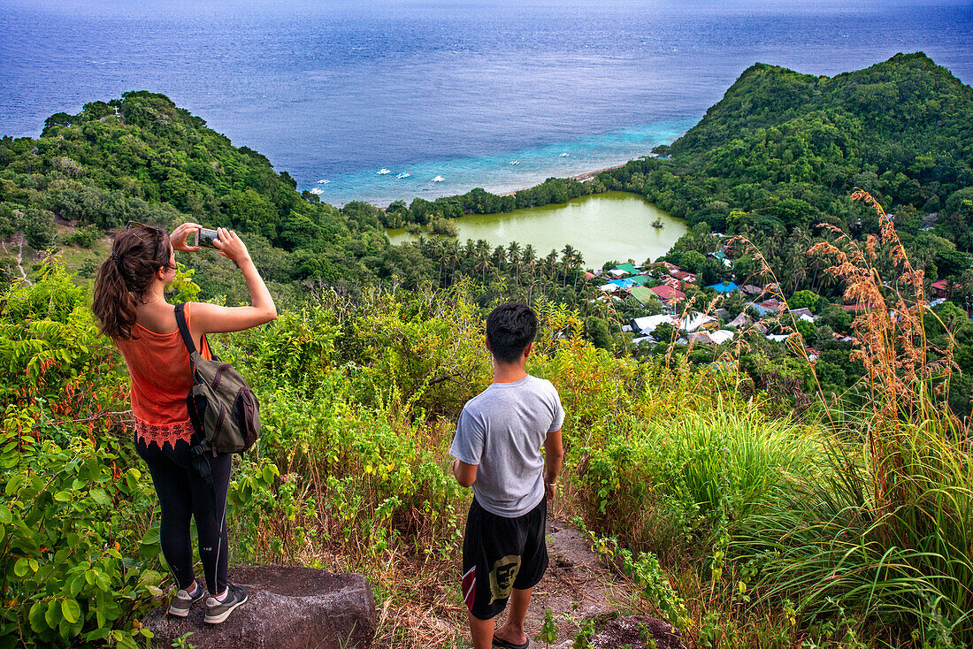 Touristen fotografieren in einer Lagune an der Felsenküste von Apo Island, Dauin, Negros Oriental, Philippinen.