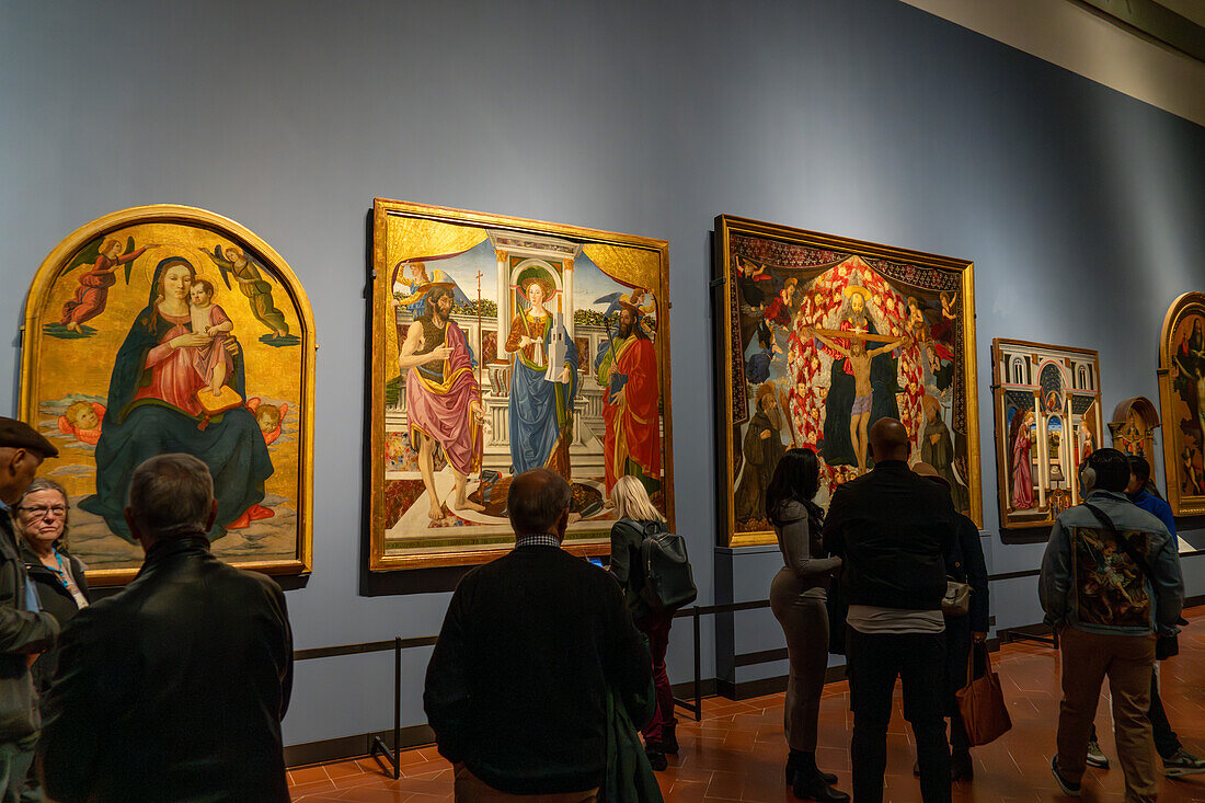 Visitors viewing Renaissance paintings in an exhibition hall in the Accademia Gallery in Florence, Italy.