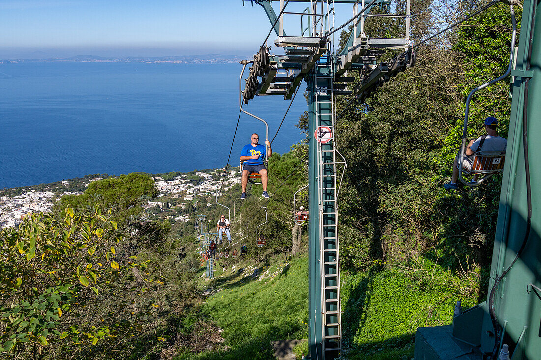 Touristen auf dem Monte Solaro Sessellift von Anacapri zum Monte Solaro Aussichtspunkt auf der Insel Capri, Italien. Die Stadt Anacapri ist unterhalb zu sehen.